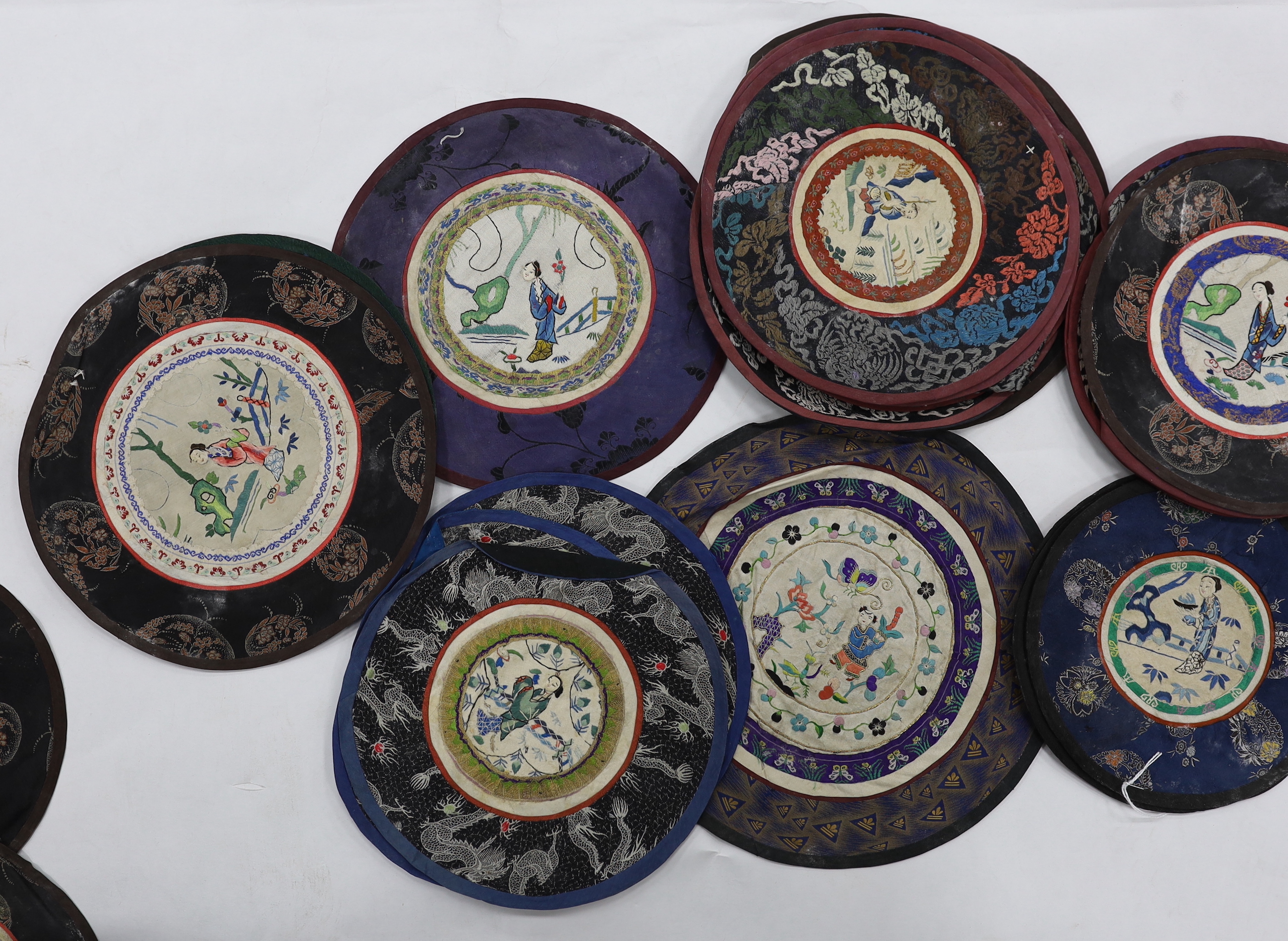 Thirty assorted Chinese silk circular mats, all embroidered with figures, all bordered with silk damask